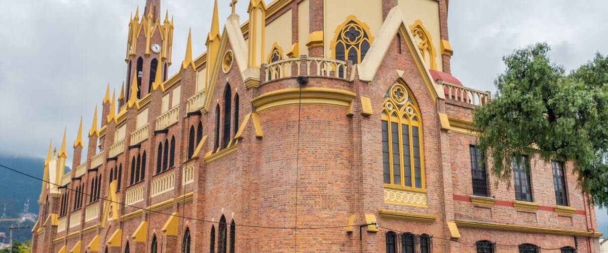 A historic church with a tall spire, ornate windows, and a brick facade.