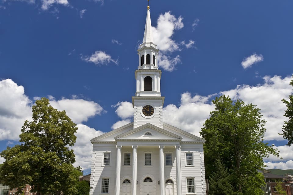 A white church with a steeple and clock tower.