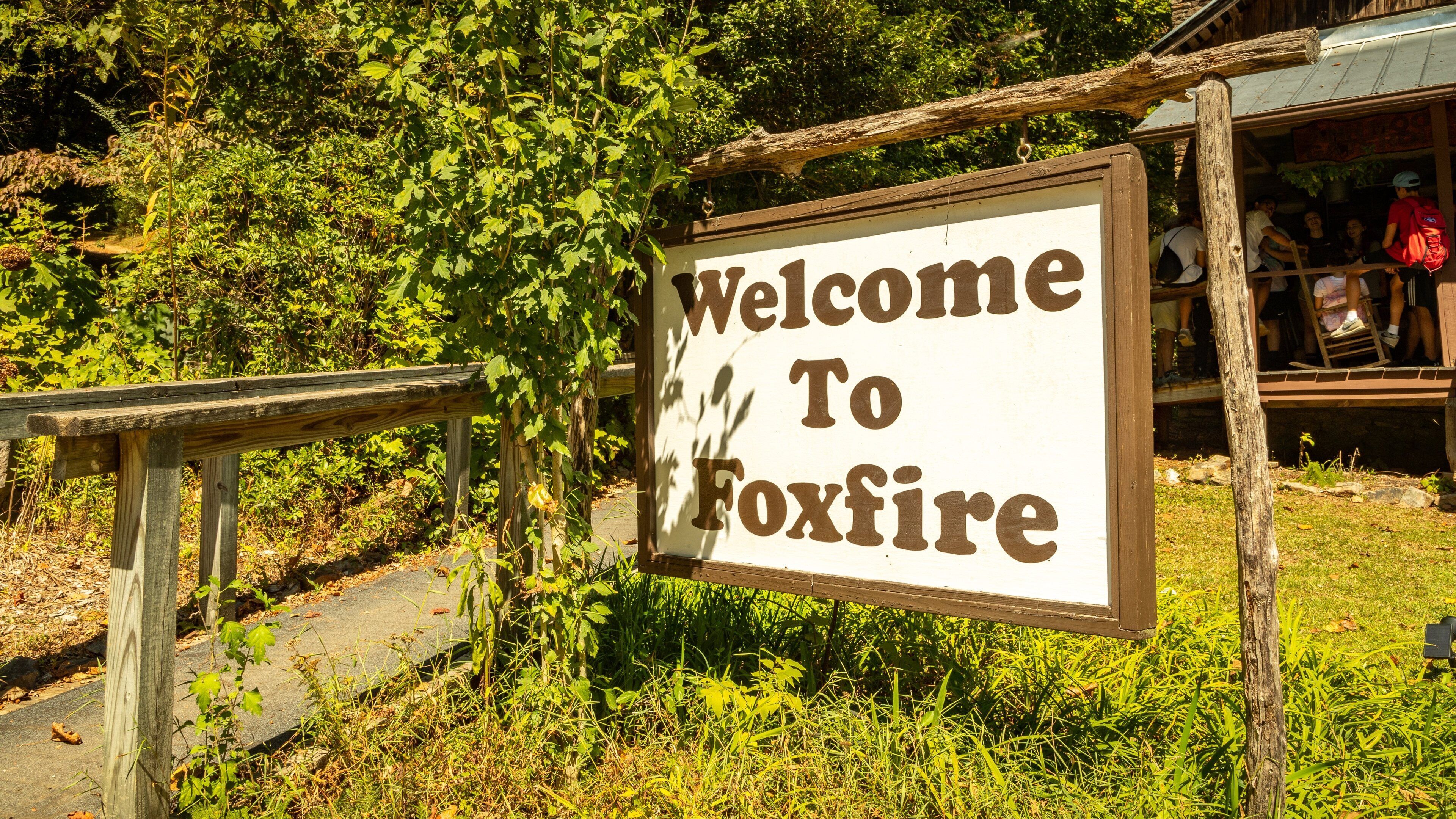 A wooden sign with the text "Welcome To Foxfire" surrounded by greenery.
