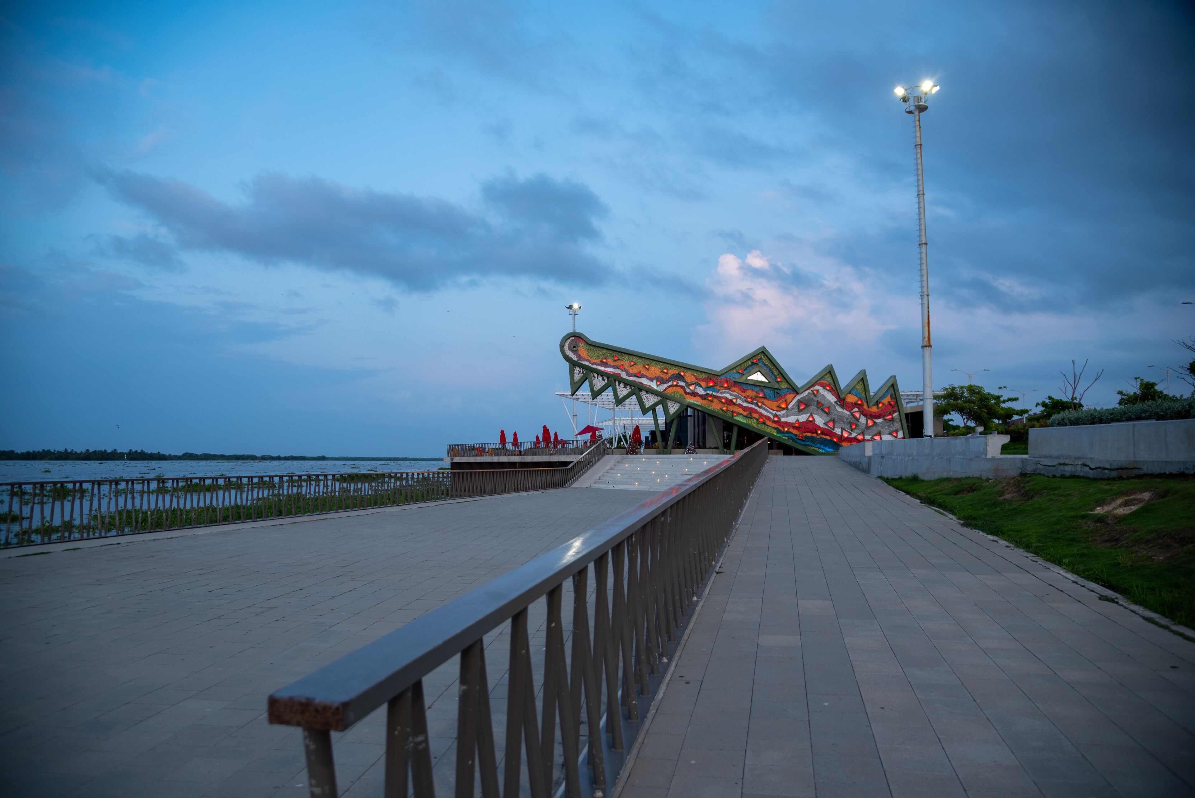 Un paseo marítimo con una estructura de puente distintiva y colorida y un alto poste de luz.