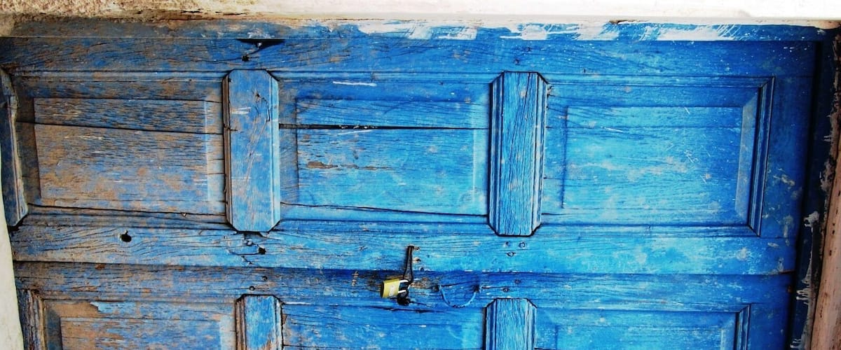 A blue wooden door with a padlock.