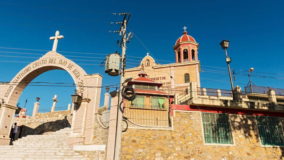 A stone church with a cross archway and a bell tower.