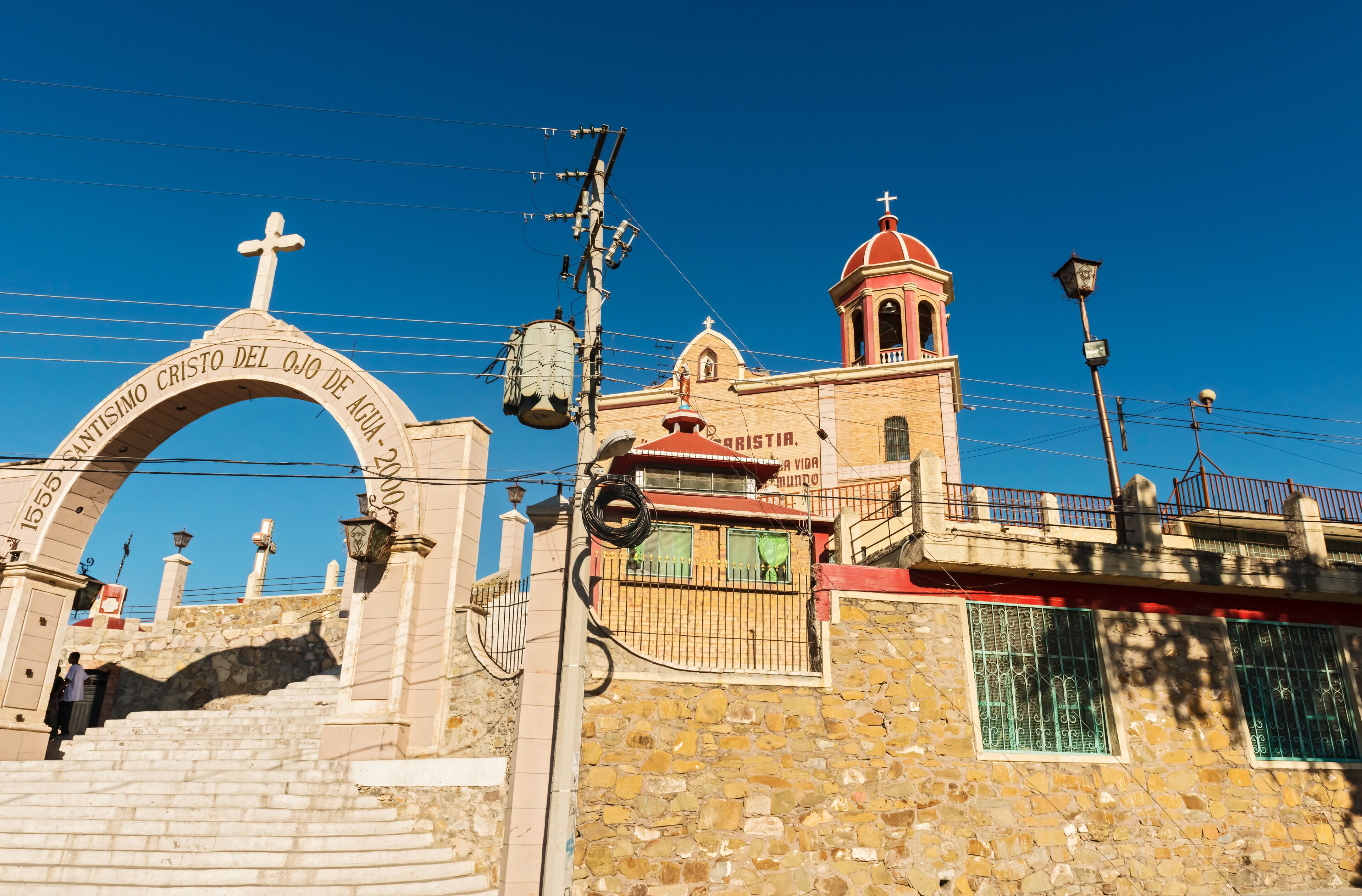 A stone church with a cross archway and a bell tower.