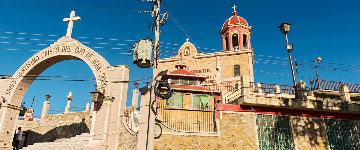 A stone church with a cross archway and a bell tower.