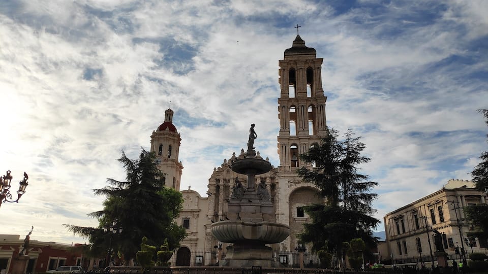 A historic church with a bell tower and a fountain in front.