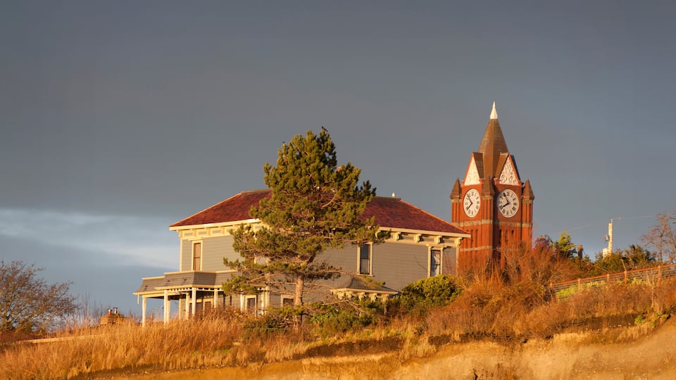 Jefferson County Courthouse Clock Tower. During sunrise, the county courthouse peaks out over the bluff along the coastline of the historic city of Port Townsend, Washington, USA.