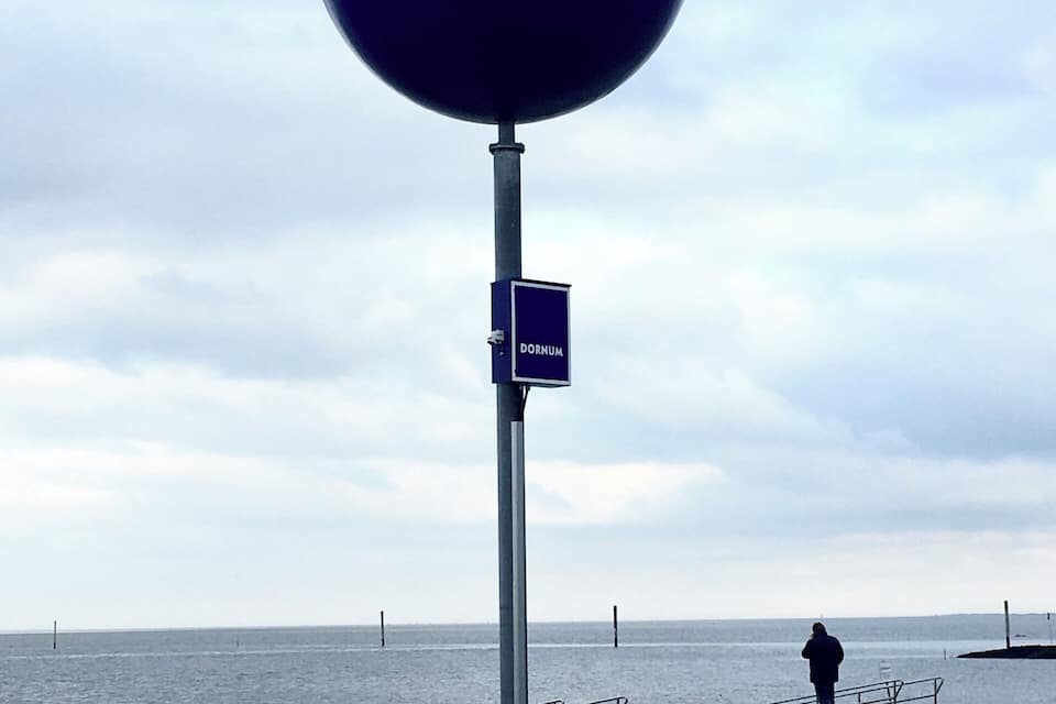 A large blue sphere with the word "NIVEA" on a beach with a person in the background.