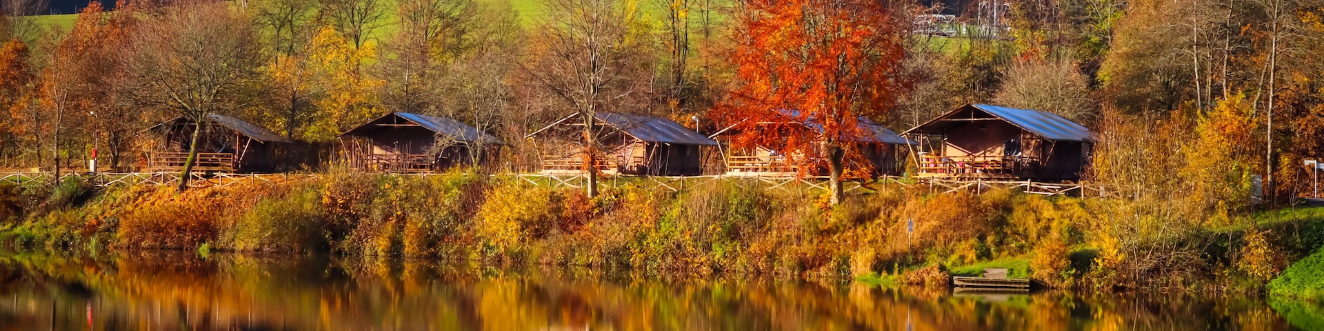 Reflection of nature, houses and bright autumn colors in the lake Wirft, Stadtkyll, Germany