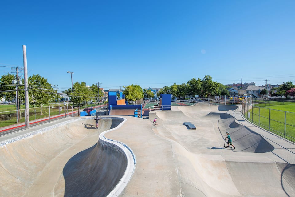 A skate park with various ramps and a fenced area.