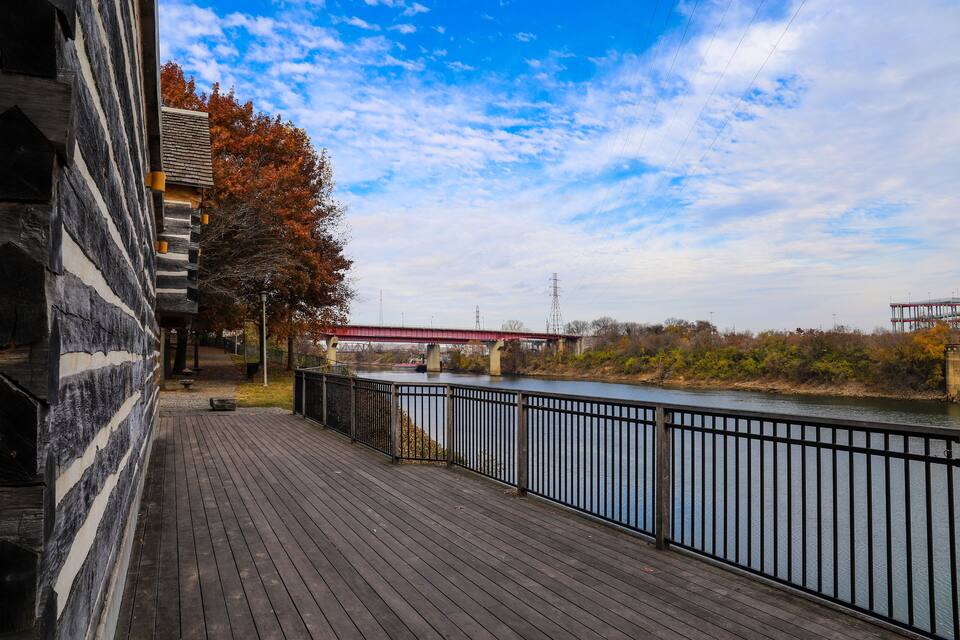 A wooden deck overlooking a river with a red bridge in the background.