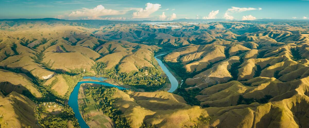 Mountain green hills panorama with curvy river, Merdeka Hill, Bukit Wairinding, East Sumba, Indonesia. Travel Background. Nature landscape. Untouched wild island. Vintage yellow toning