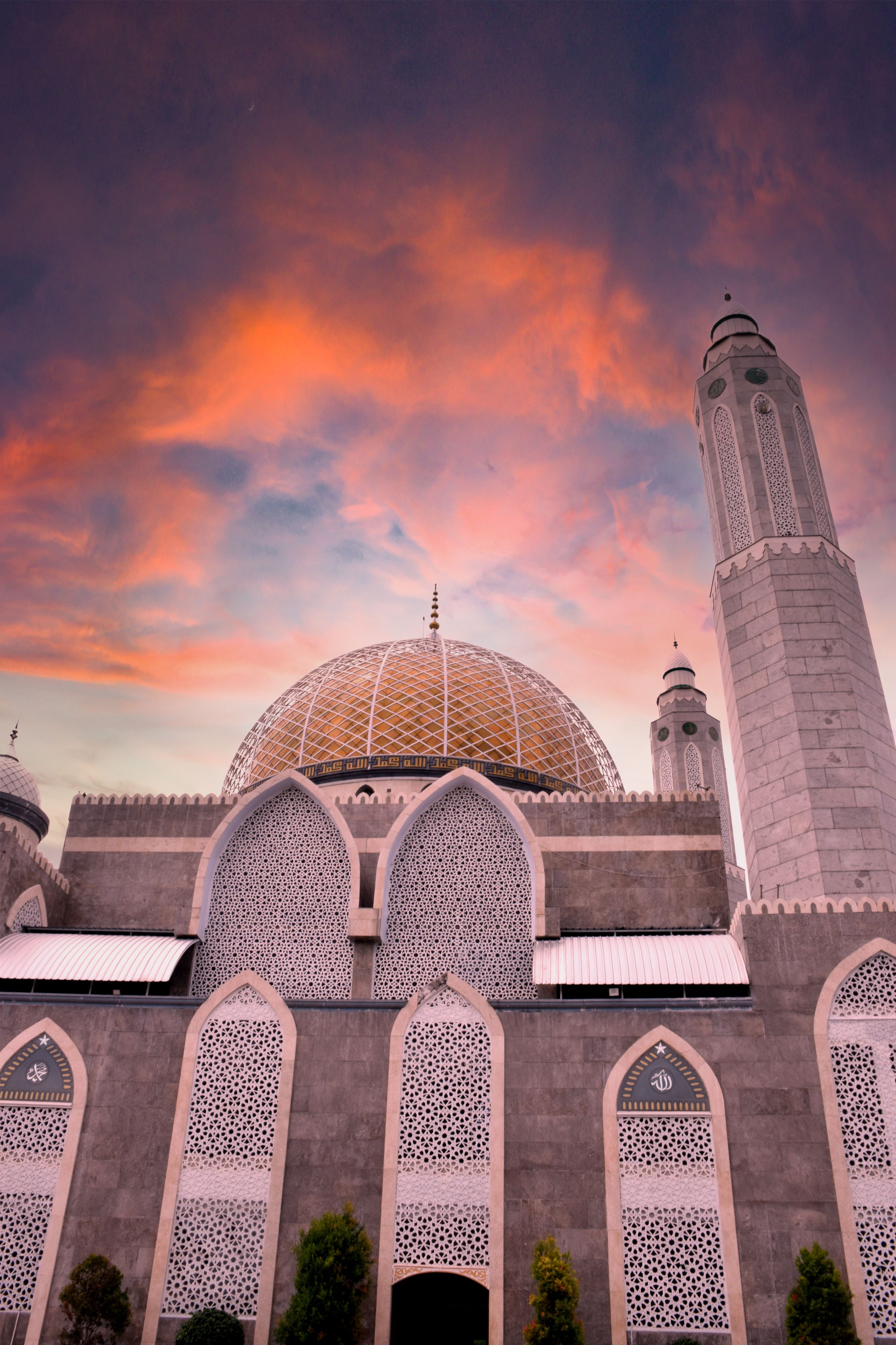 A mosque with a large golden dome, intricate lattice windows, and a tall minaret.