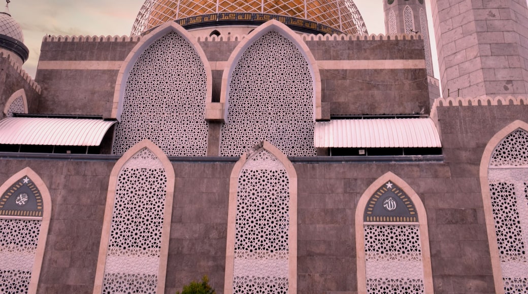 A mosque with a large golden dome, intricate lattice windows, and a tall minaret.