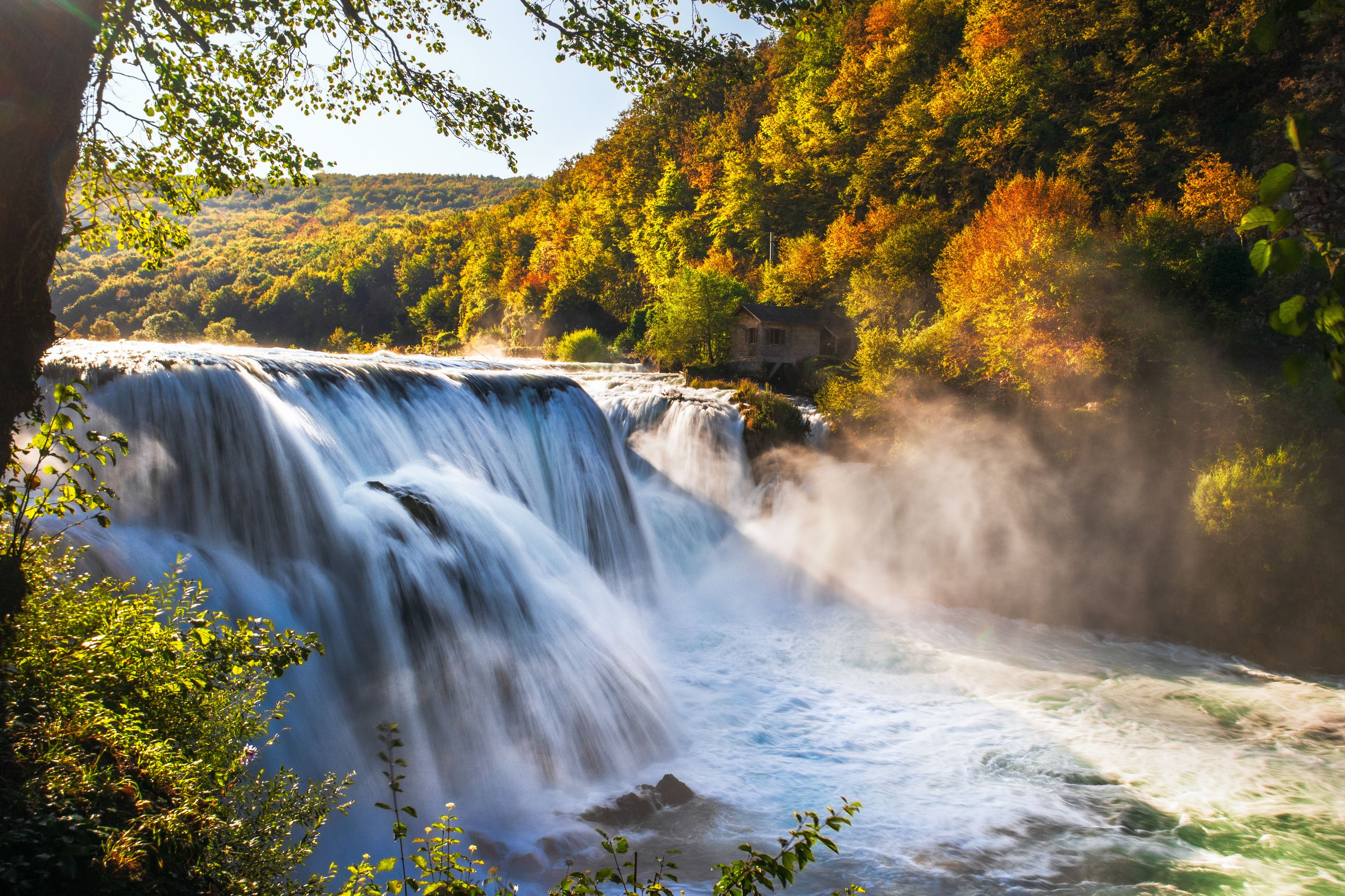 A waterfall with a house on a hill.