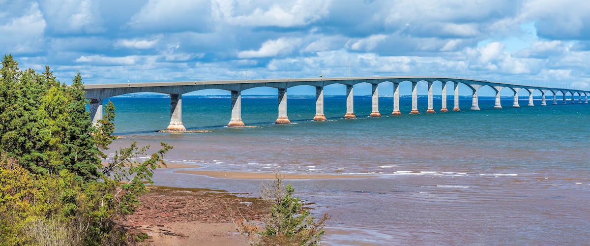 A long bridge over a body of water with a beach in the foreground.