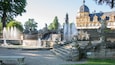 A grand fountain with multiple water jets, a stone staircase, and ornate statues.