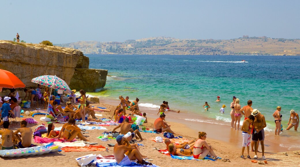 Bugibba Beach featuring a sandy beach as well as a large group of people