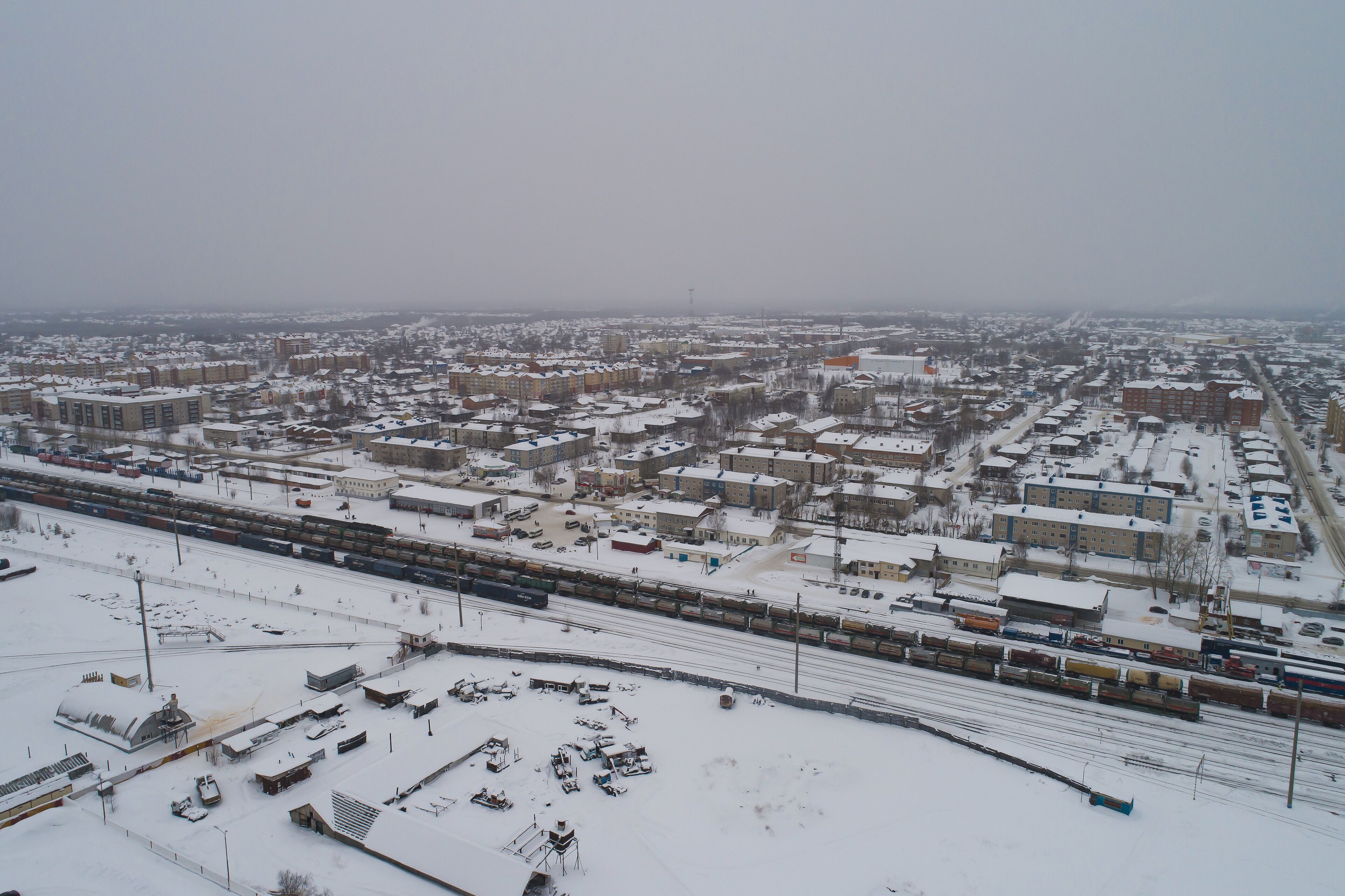 Sovetskiy city. Railway station Verkhnekondinskaya and the trains.  Aerial. Winter, snow, cloudy. Khanty Mansiysk Autonomous Okrug (HMAO), Russia.