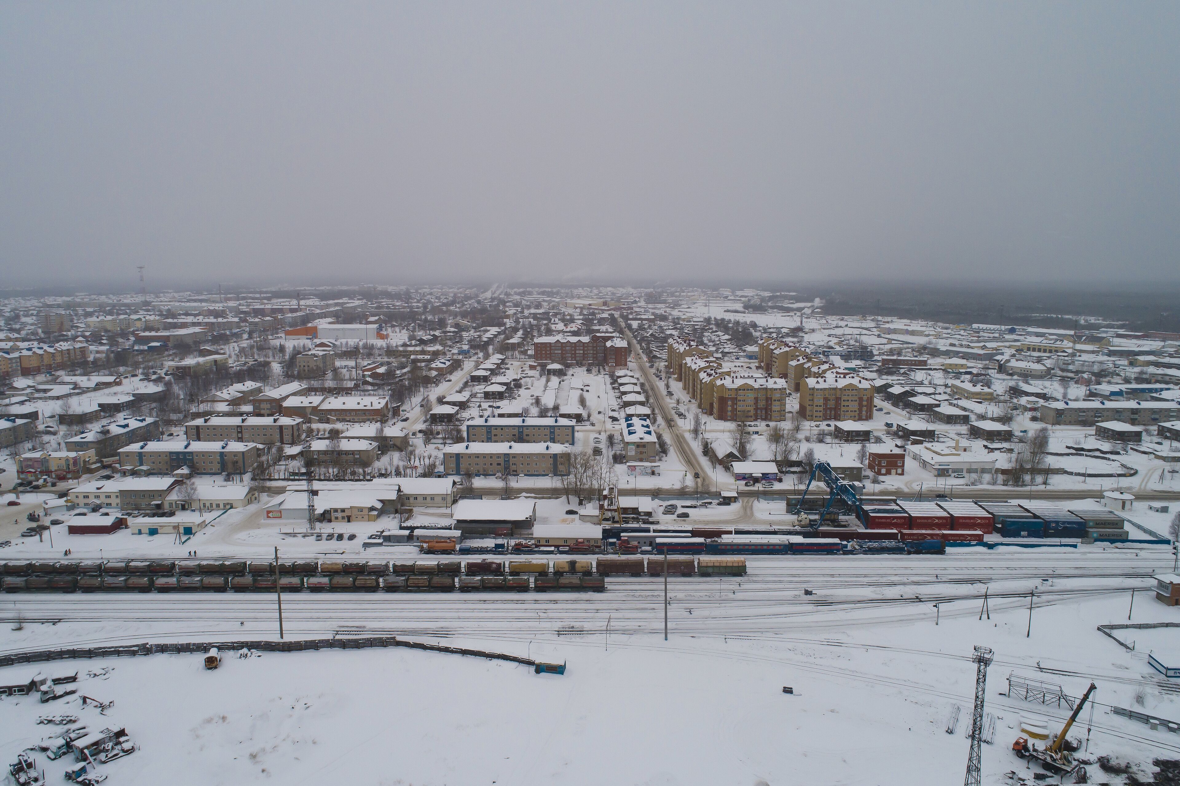 Sovetskiy city. Railway station Verkhnekondinskaya and the trains.  Aerial. Winter, snow, cloudy. Khanty Mansiysk Autonomous Okrug (HMAO), Russia.
