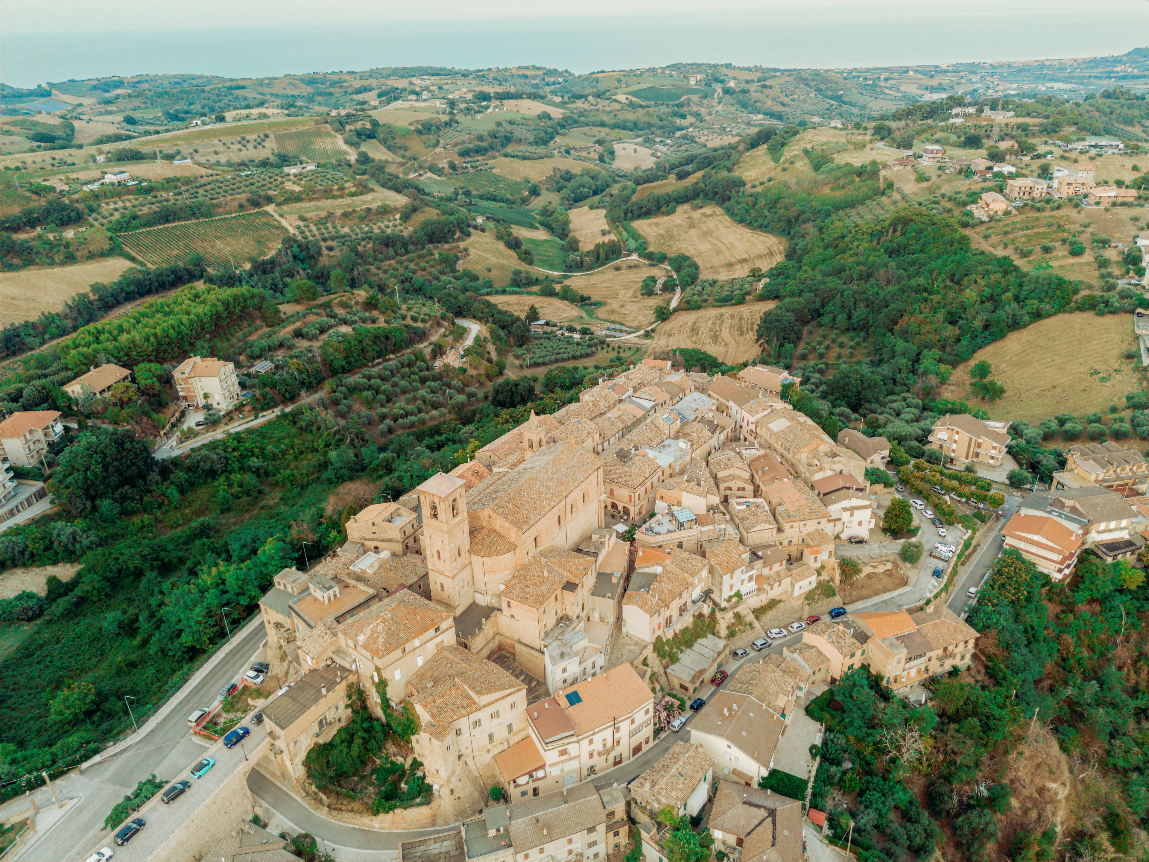 Aerial view of the historic town of Montefiore dell'Aso with terracotta rooftops and a church bell tower surrounded by rolling hills in Montefiore dell'Aso, Marche, Italy.