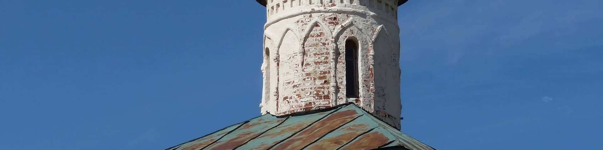A church with a green onion dome and a cross on top.
