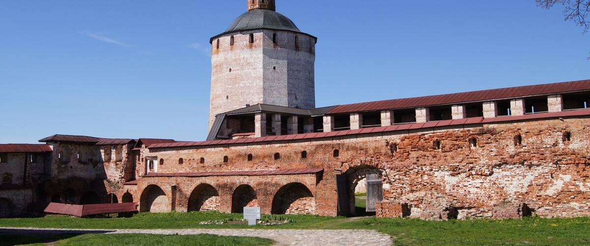 A historic brick building with a prominent tower and arched passageways.