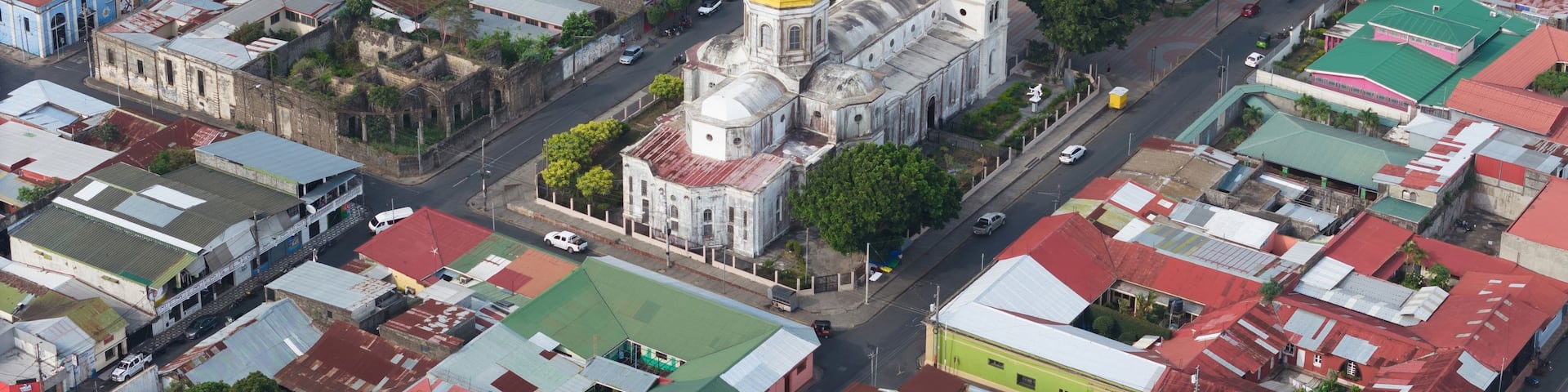 An aerial view of a densely packed urban area with colorful buildings, a prominent church with a golden dome, and a grid of streets.