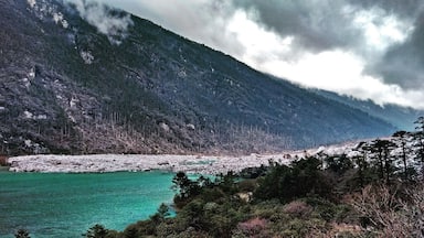 A turquoise lake surrounded by forested mountains and rocky shores.