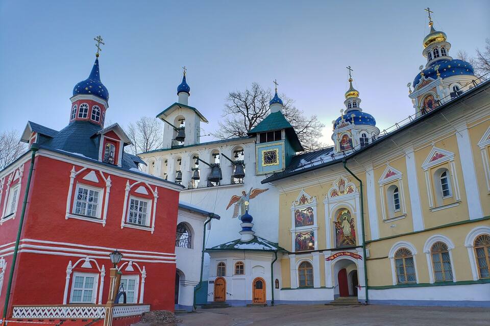 Uma igreja com cúpulas coloridas e um edifício vermelho com detalhes brancos.