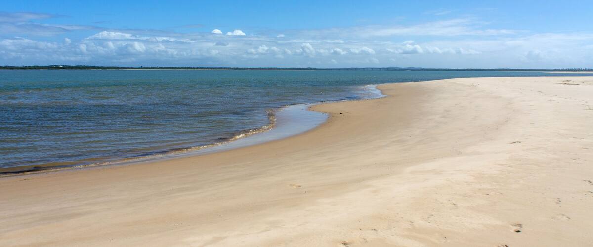A wide sandy beach with gentle waves lapping at the shore.