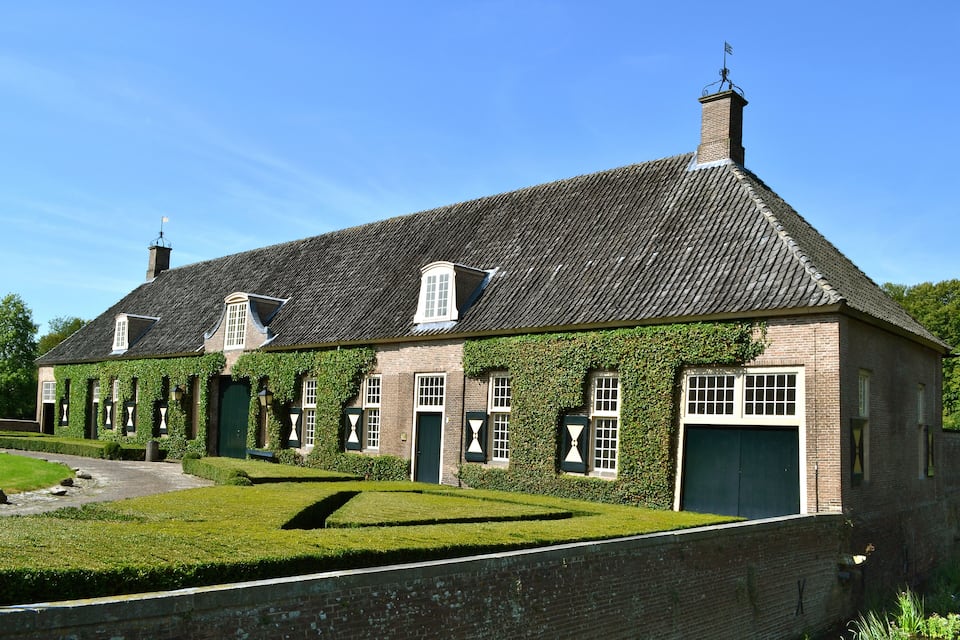 Een historisch gebouw met muurranken, een baksteenvoorgevel en een traditioneel pannendak.