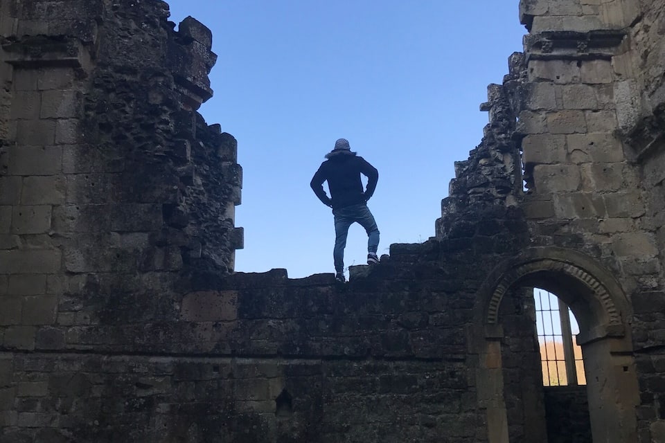 A person standing in a ruined stone structure with an arched doorway.