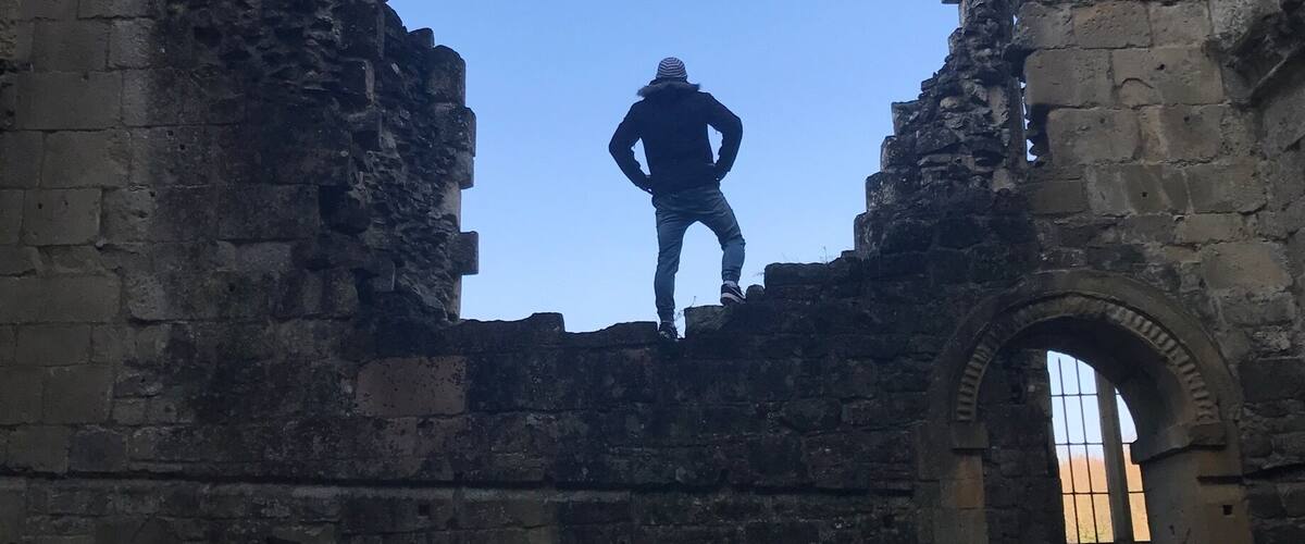 A person standing in a ruined stone structure with an arched doorway.