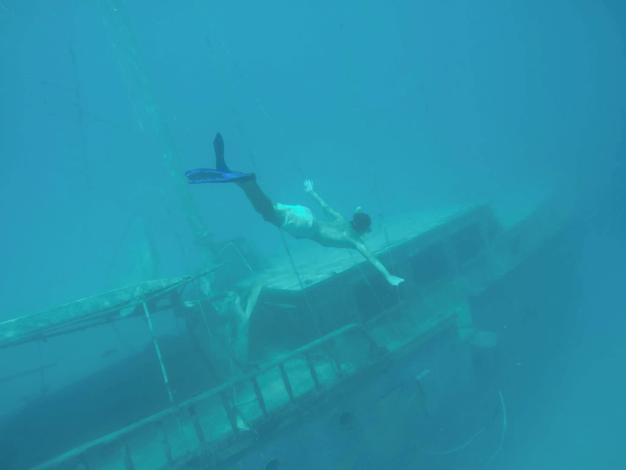 A diver underwater near a shipwreck.