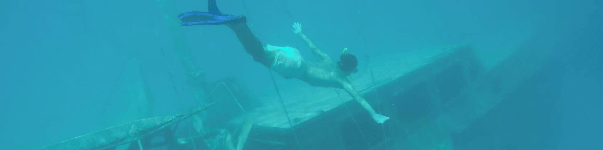 A diver underwater near a shipwreck.