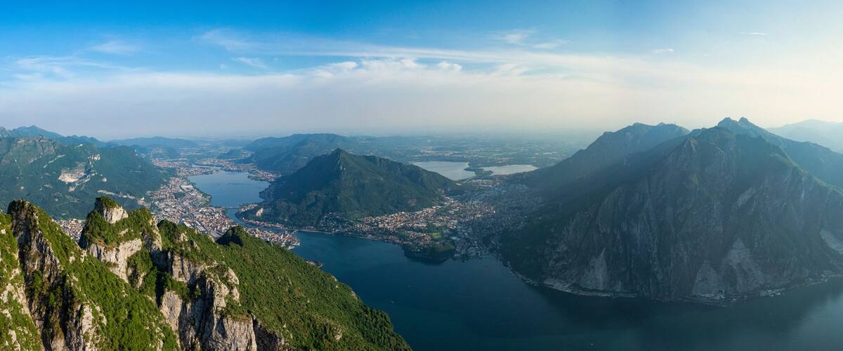 A mountainous landscape with a city nestled between peaks and a large body of water.