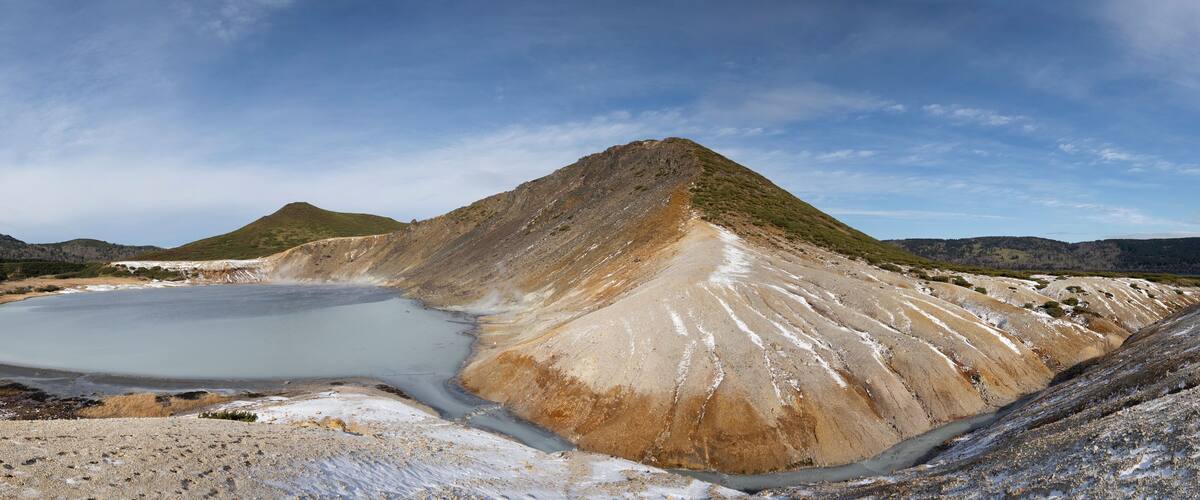 A large salt flat with a small lake and a prominent hill.