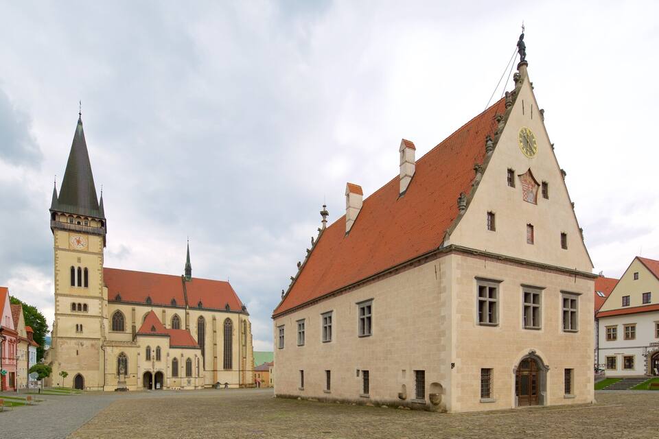 Ett historiskt torg med en framträdande kyrka som har ett högt torn och ett klocktorn.