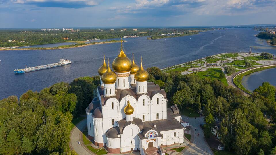 A cathedral with golden domes by a river.