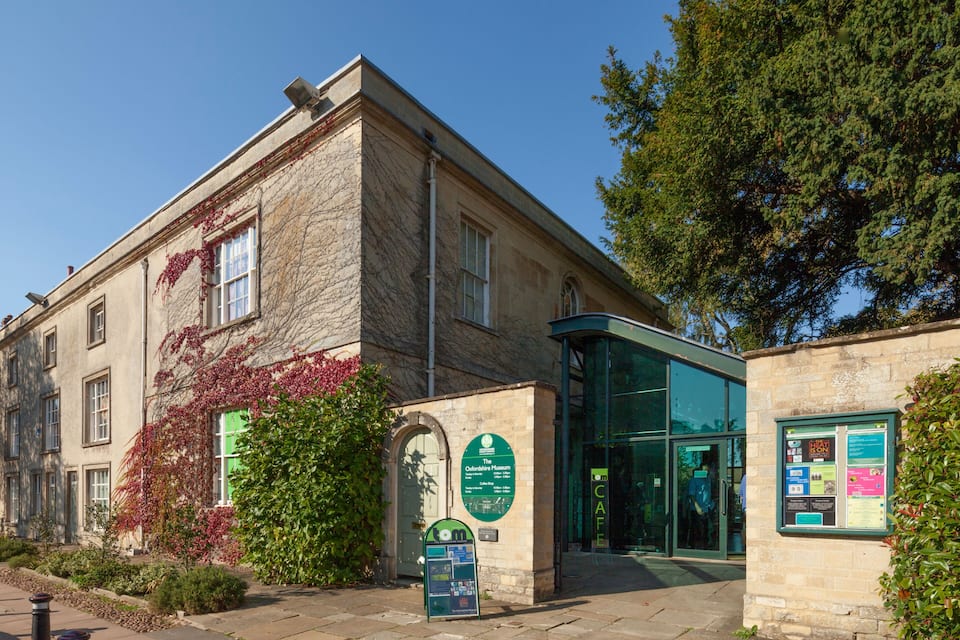 A historic building with ivy, a glass entrance, and informational signs.