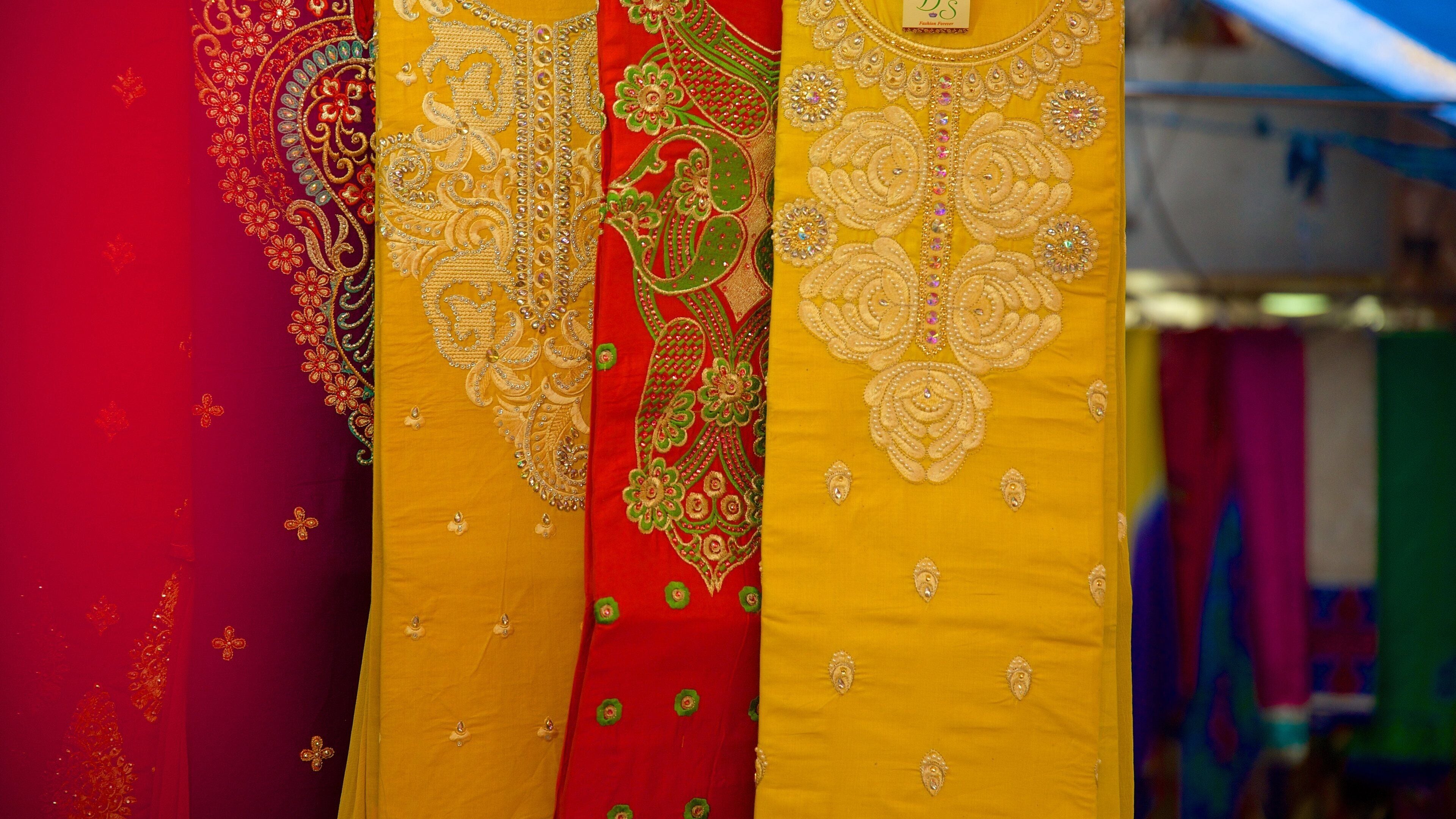 A variety of richly embroidered fabrics in red, yellow, and green.