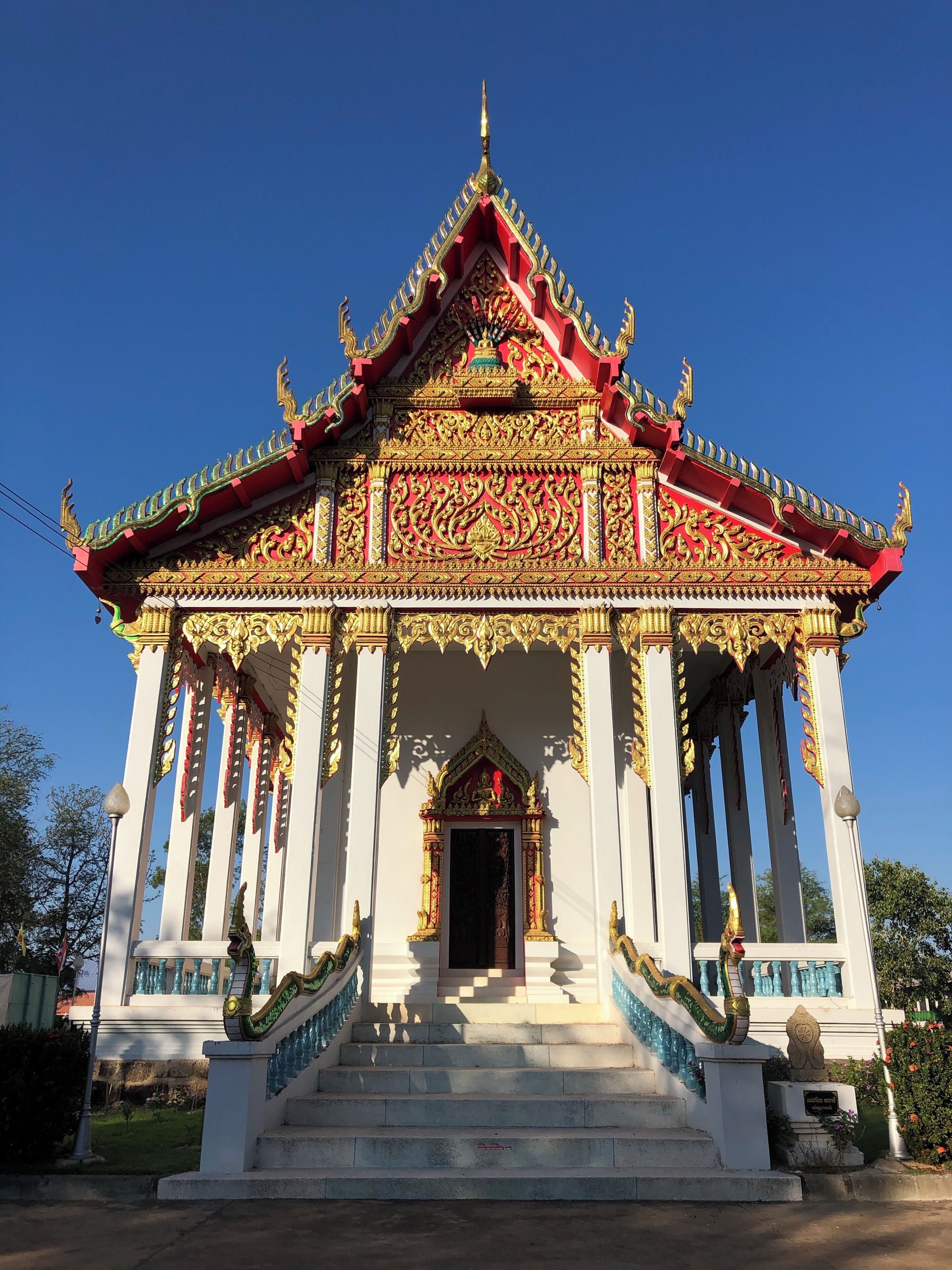 A traditional Thai temple with ornate golden decorations and a red roof.