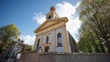 Uma igreja histórica com uma torre de sino, janelas em arco e uma parede de tijolos.
