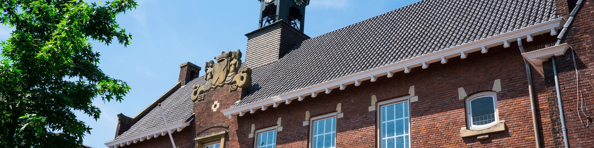 Un edificio histórico con una torre de reloj, ventanas grandes y fachada de ladrillo.