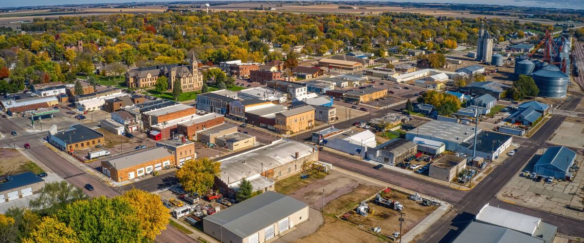 An aerial view of a town with industrial buildings, a church, and surrounding fields.