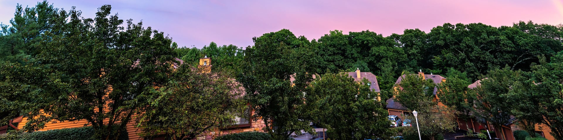 A rainbow arching over a suburban neighborhood with houses and trees.