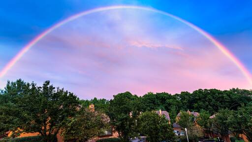 Spectacular rainbow above a New Jersey suburban community with wooden houses.