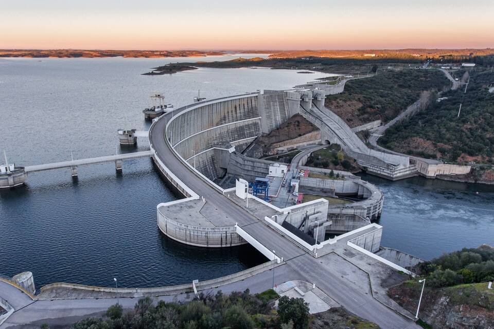 Uma grande barragem com vertedouro curvo e sistema de eclusas.