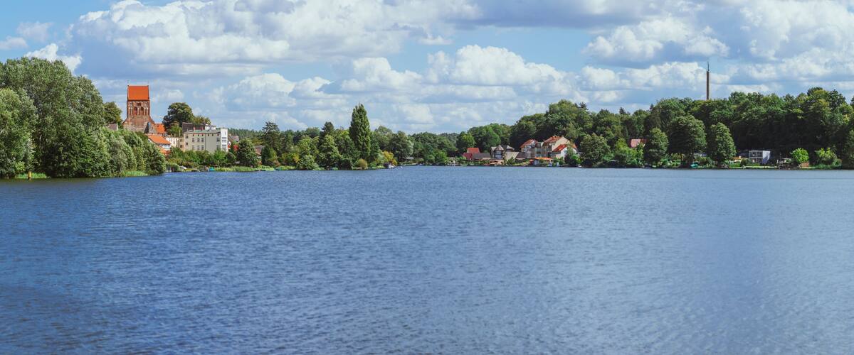 A calm lake with a historic church and residential buildings on the shore.