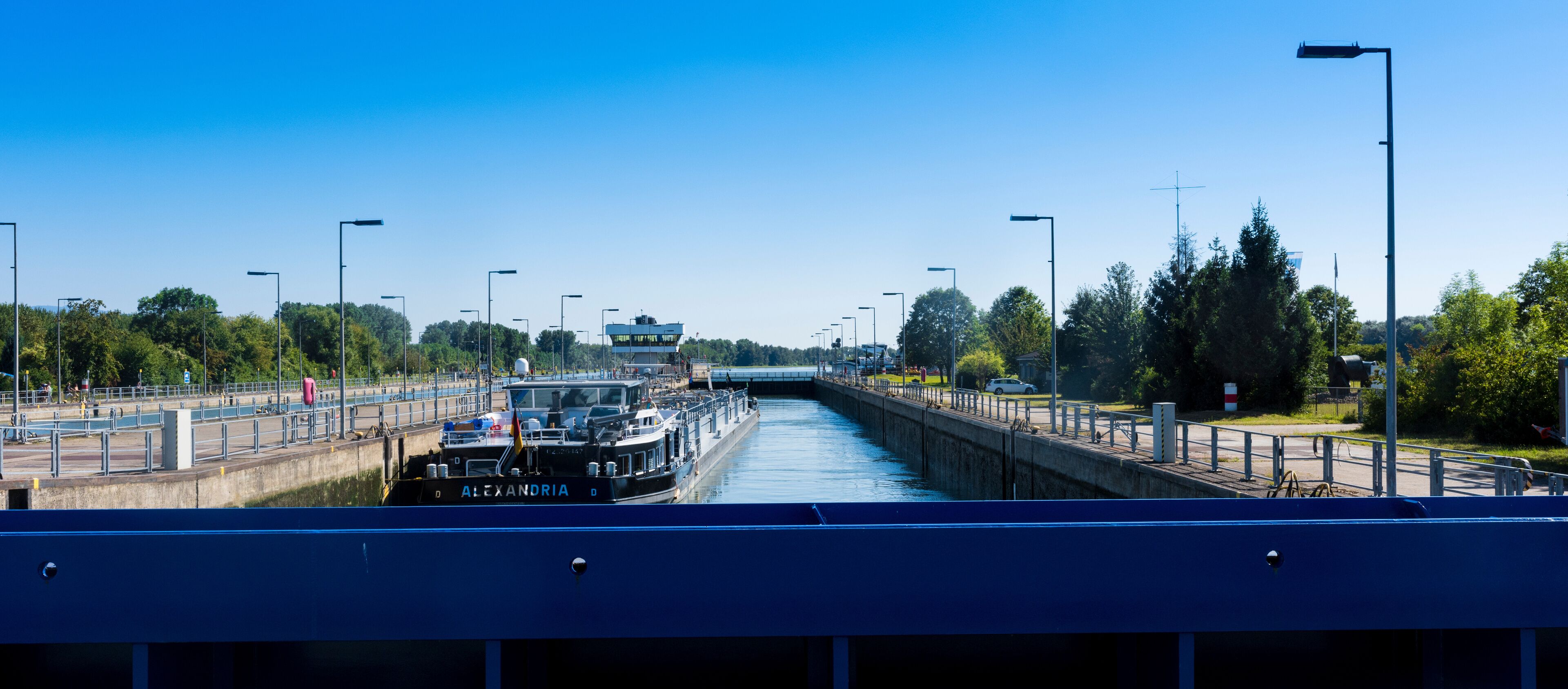 A narrow waterway with a boat named "Alexandria" passing under a bridge.
